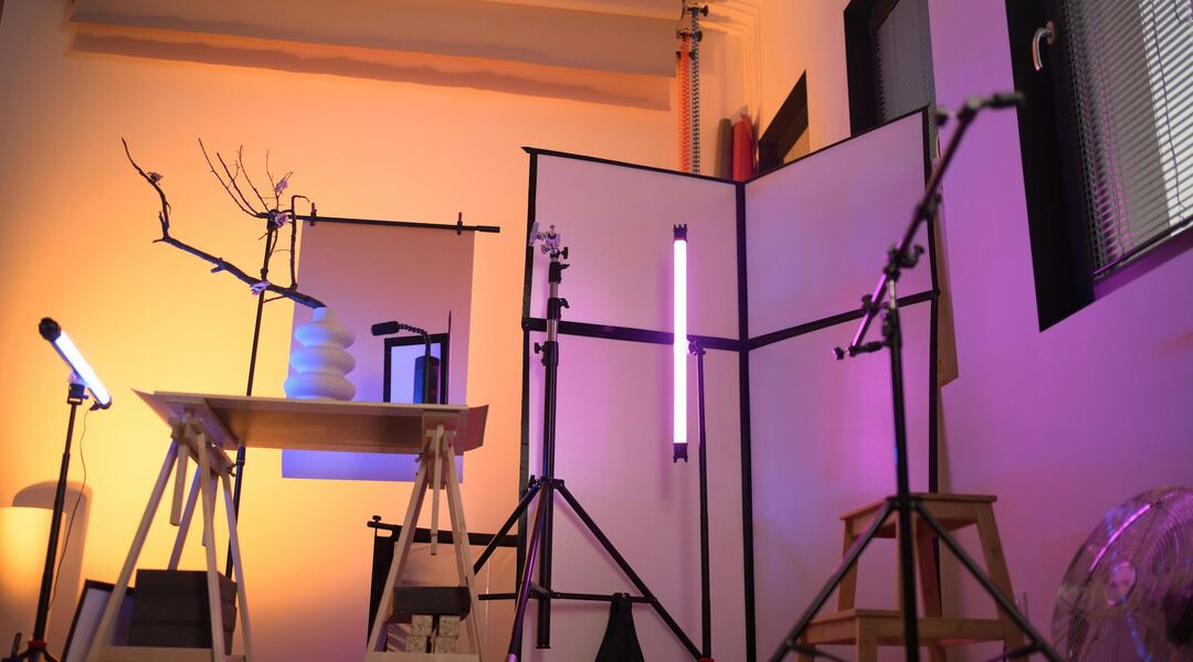 Kreatives Aufnahmestudio mit bunter Beleuchtung, Lichtstativen und Mikrofonen