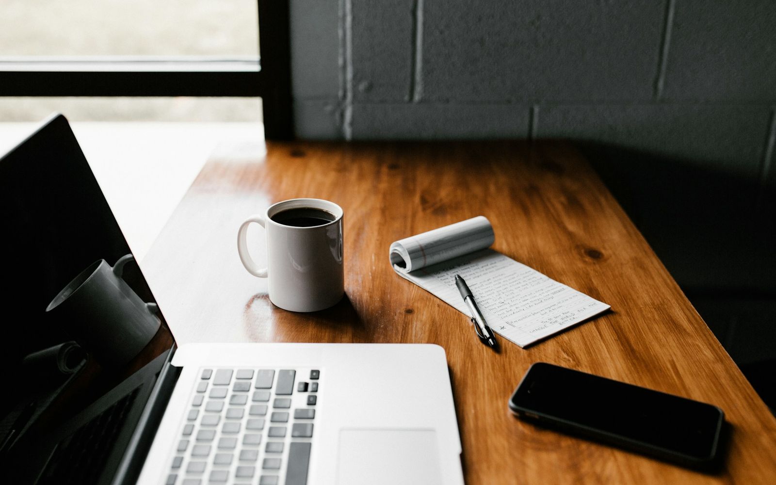 Arbeitsplatz mit Notizbuch, Laptop und Kaffee für die Content-Planung