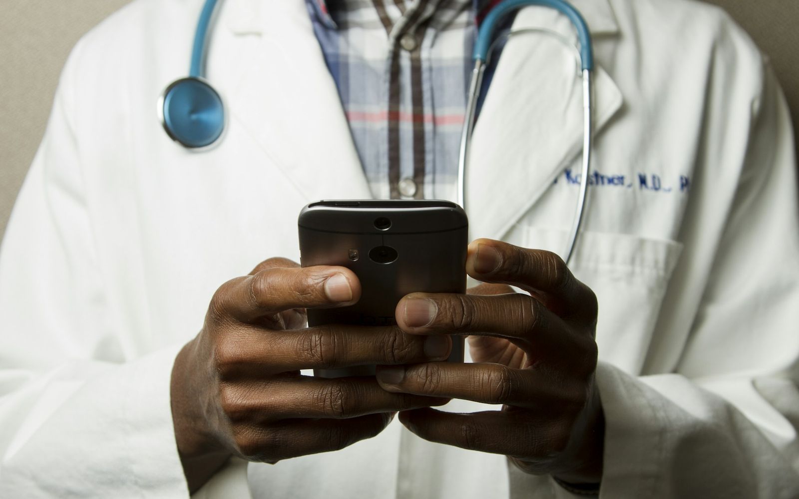 Ärztin im weißen Kittel beantwortet die Patientenanfrage auf dem Smartphone, Marketing für Gesundheitstourismus